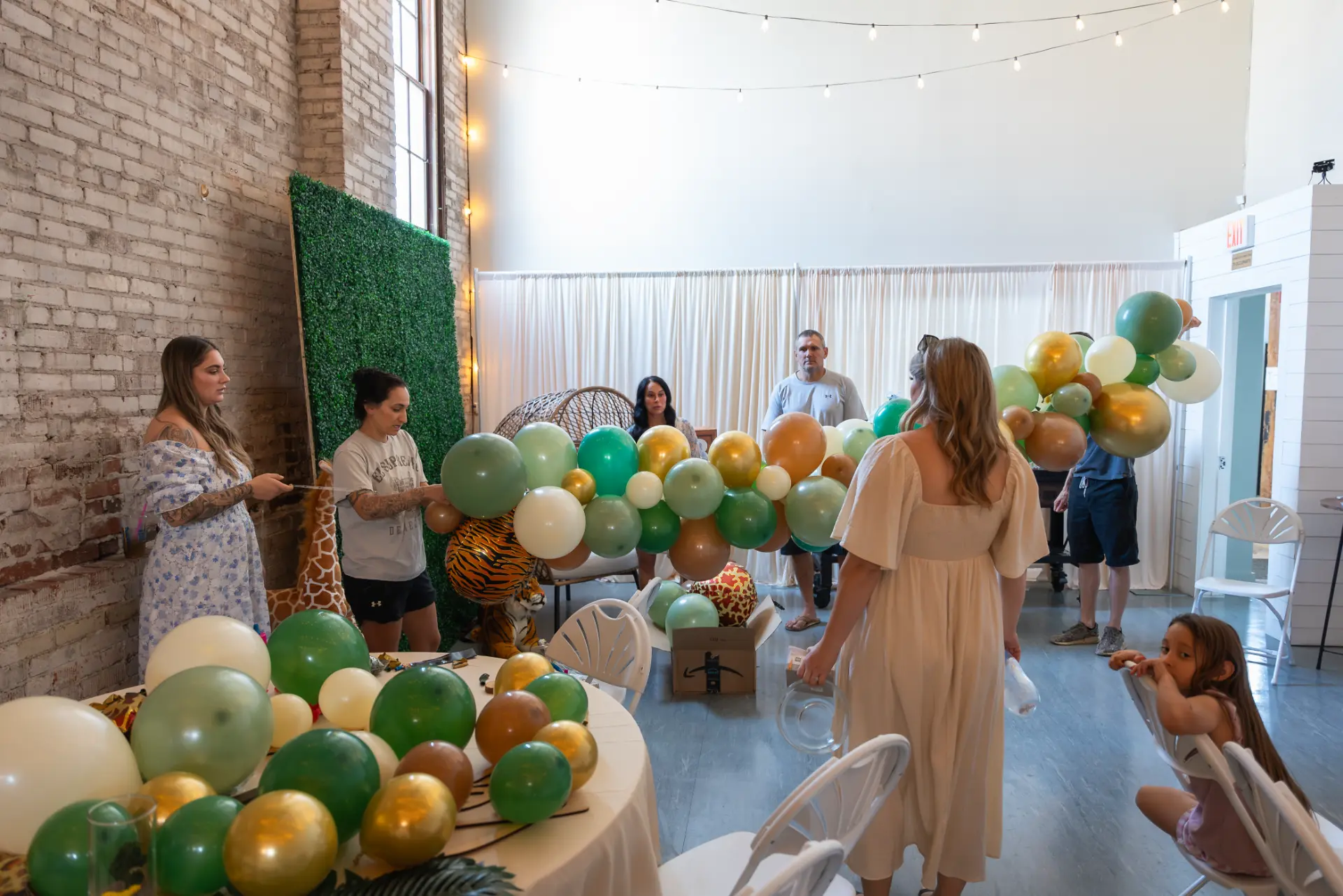 Family setting up a safari baby shower with balloon garlands and greenery wall in the Host Wenatchee event space