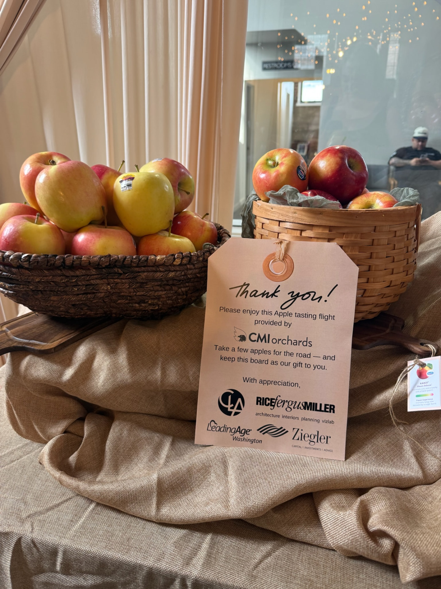 Apple tasting flight baskets with a sponsor thank-you card at a corporate reception in Wenatchee