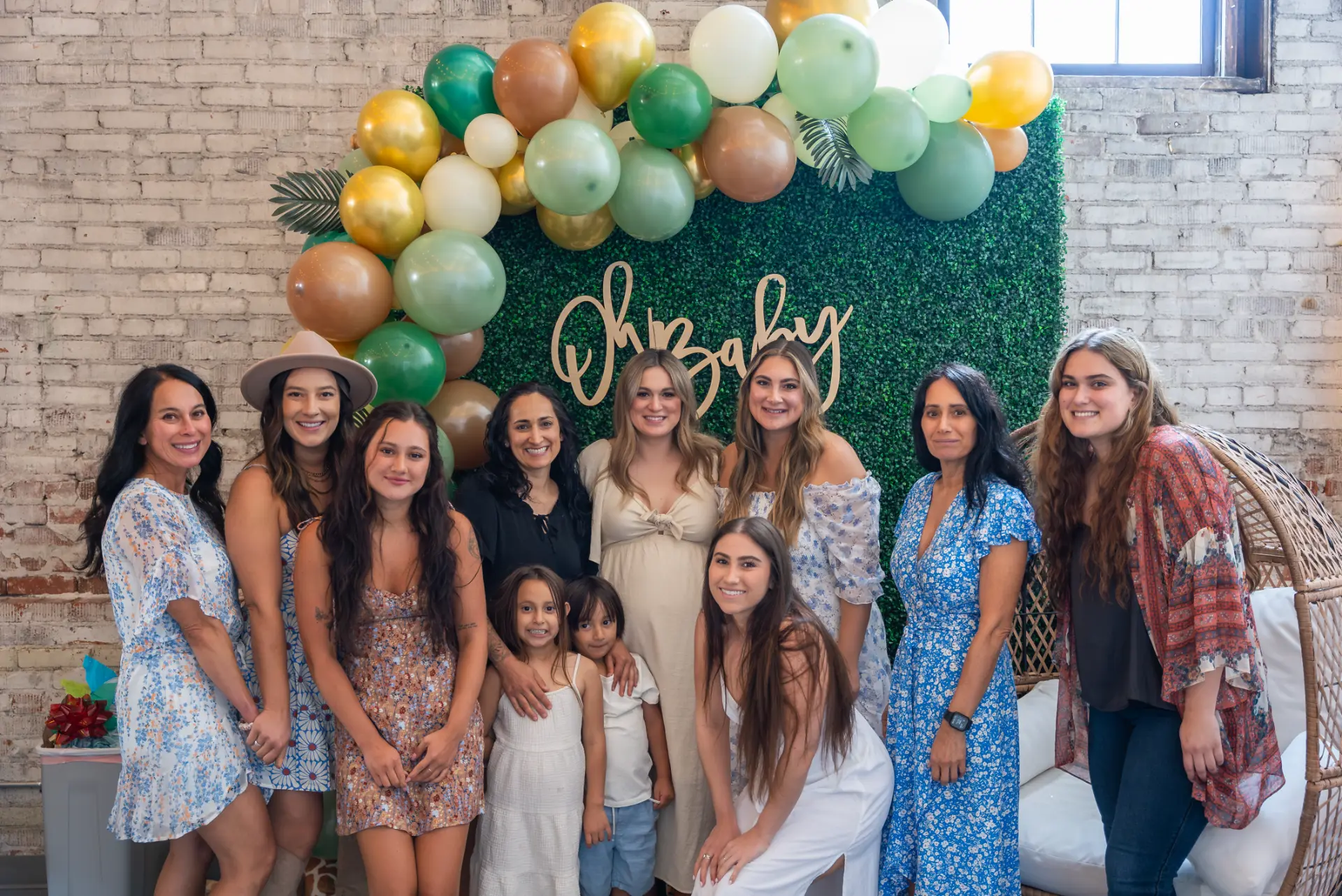 Guests posing at an Oh Baby greenery and balloon backdrop at Host Wenatchee