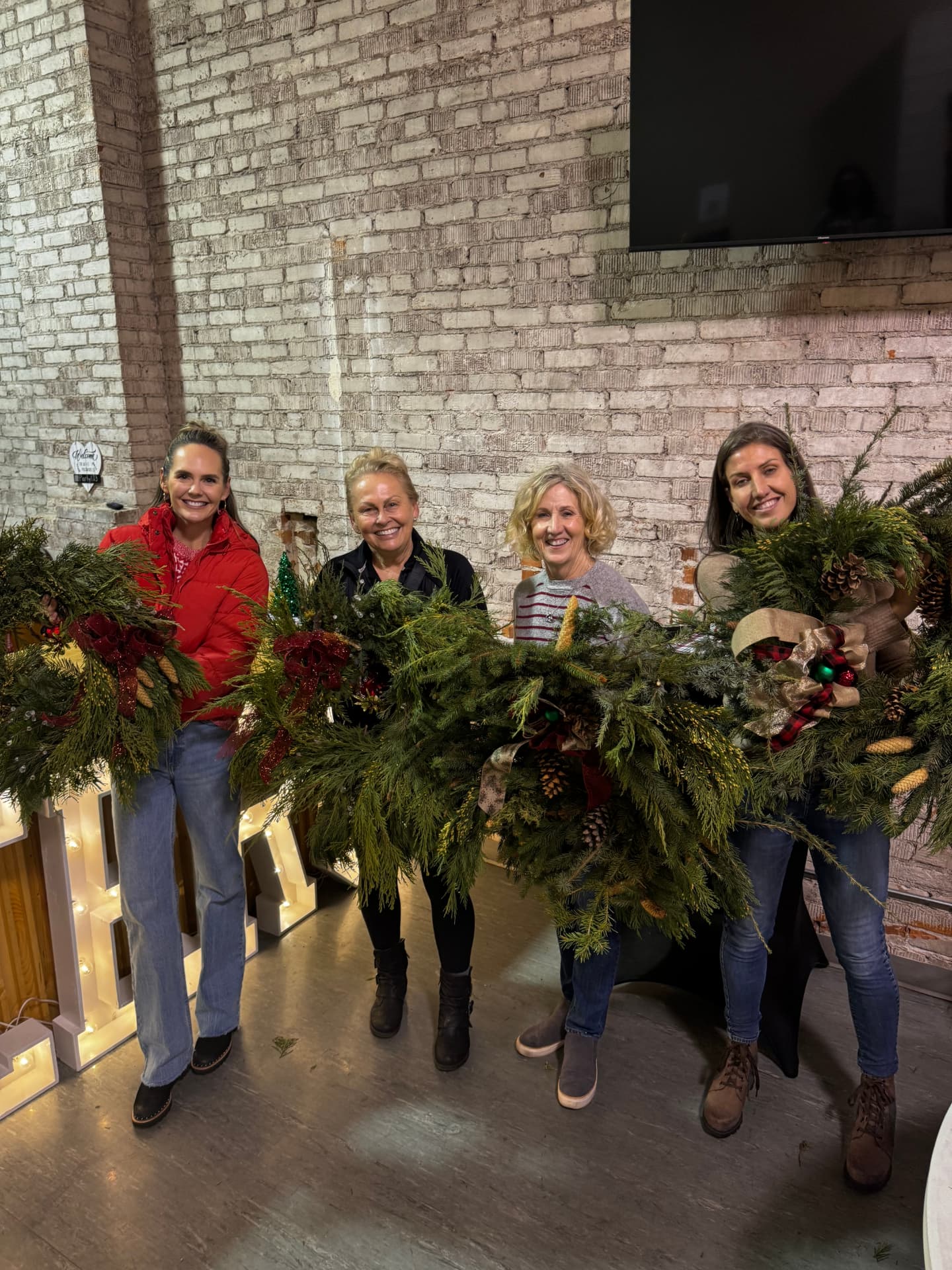 Guests holding fresh cedar and pine wreaths they built at a holiday wreath-making workshop at Host Wenatchee