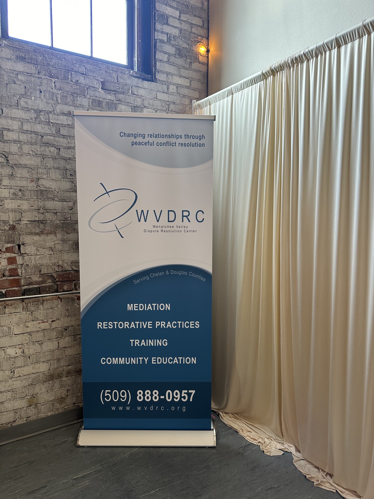 WVDRC nonprofit banner beside ivory draping and exposed brick at a corporate event in downtown Wenatchee