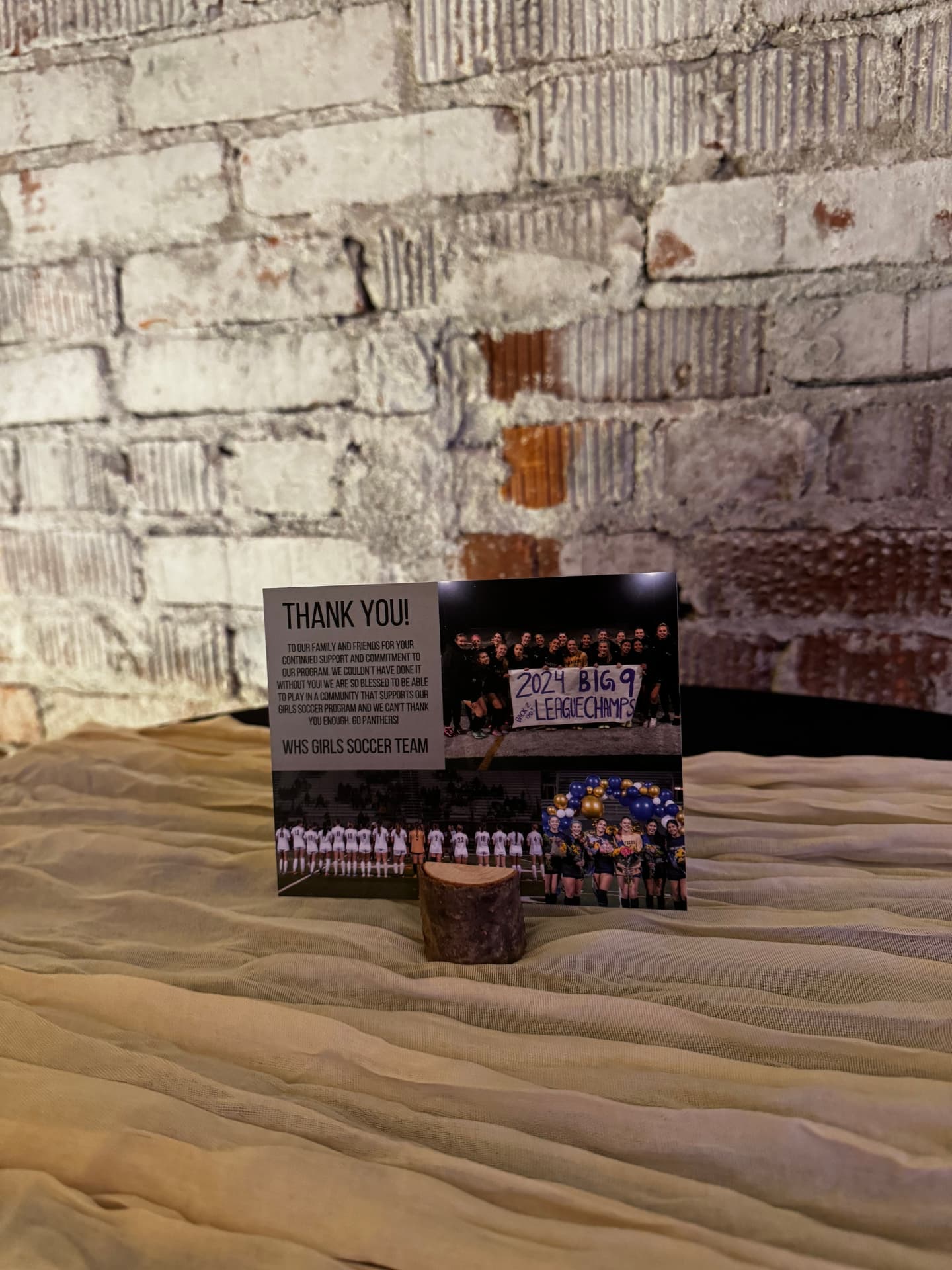 Thank-you keepsake card on a draped table against the white brick wall at Host Wenatchee