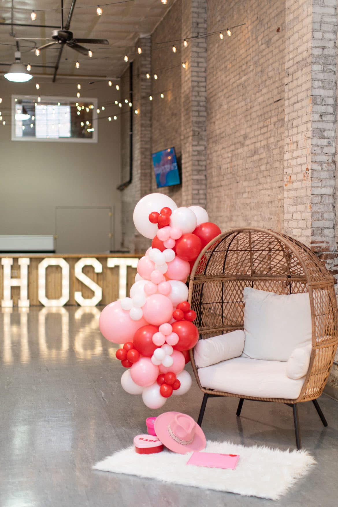 Pink and red balloon garland in front of the light-up HOST marquee letters