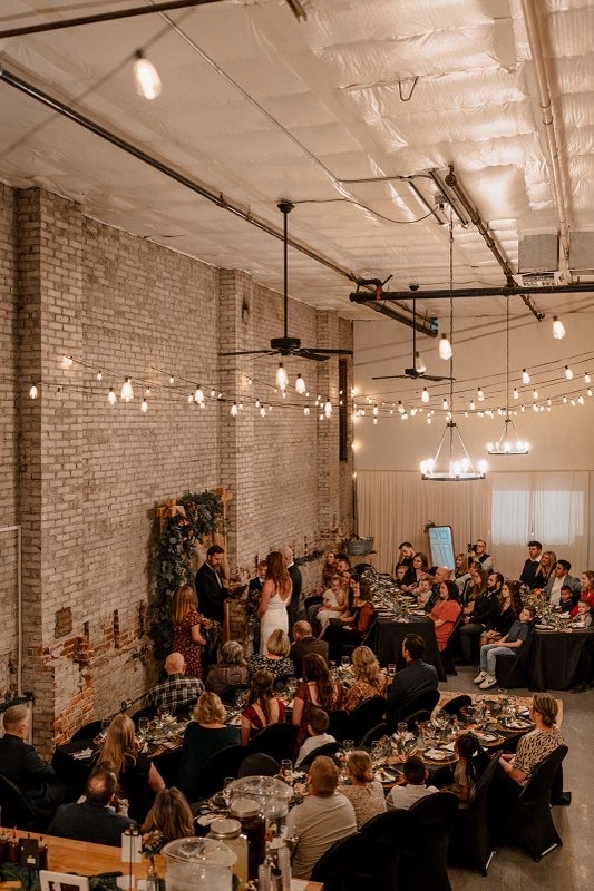 Wedding ceremony under string lights and exposed brick at Host Wenatchee