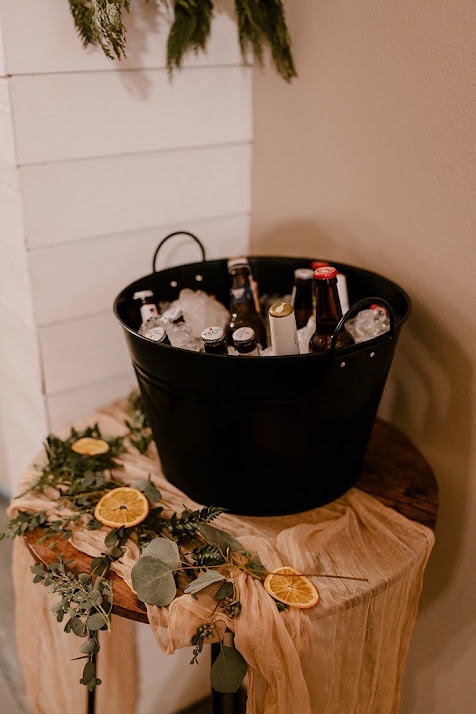 Beverage tub of iced bottled drinks styled with greenery and dried citrus at a Host Wenatchee wedding