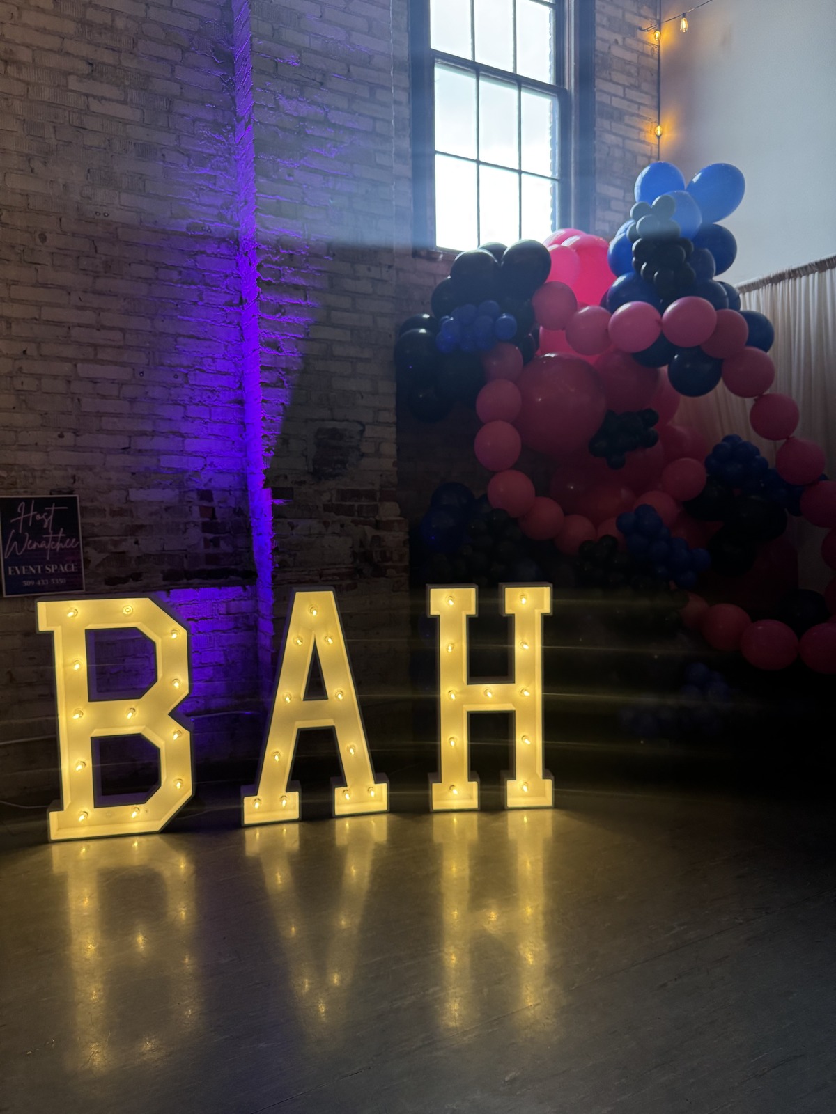 Light-up BAH marquee letters and a navy and pink balloon arch at a Business After Hours event in Wenatchee