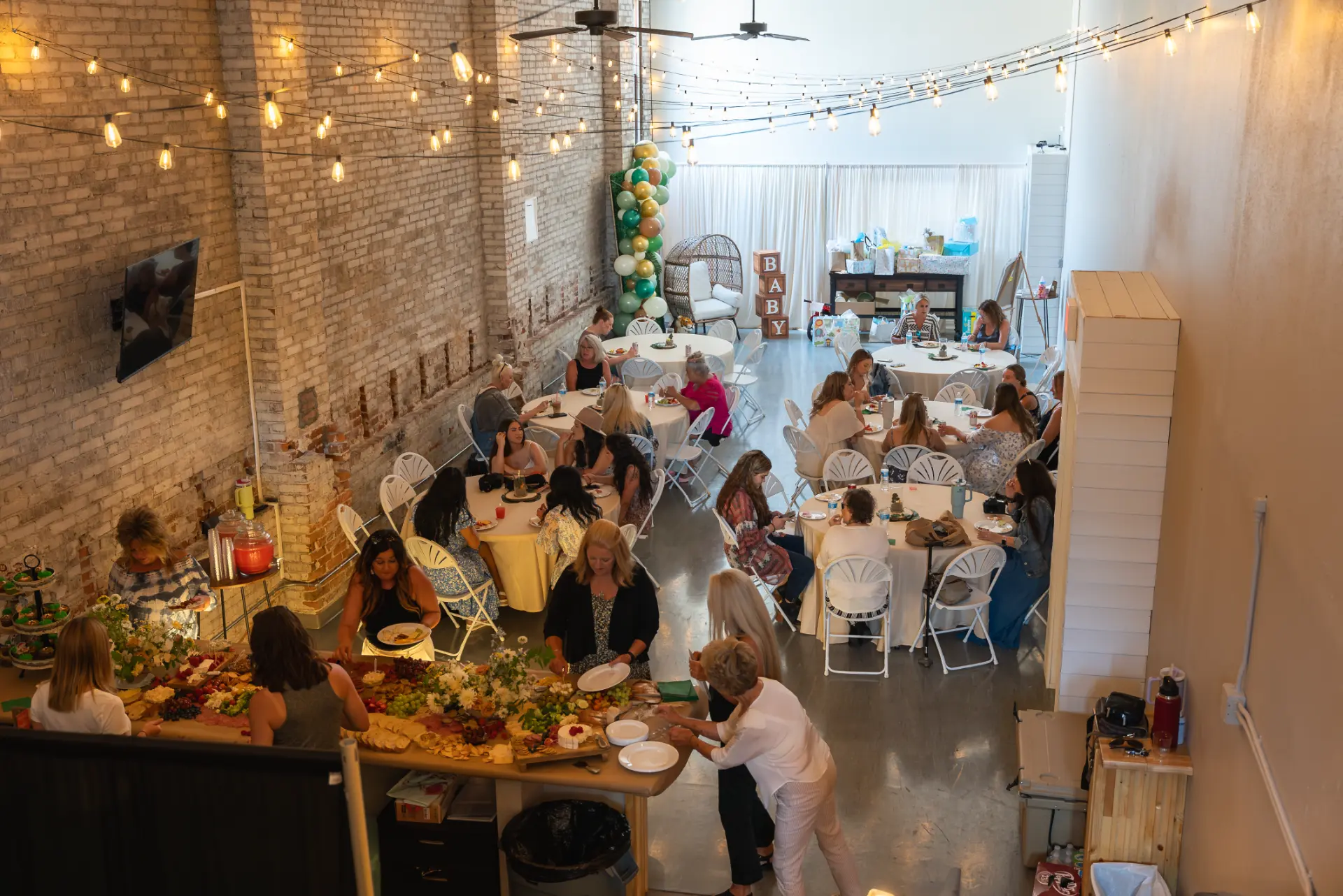 Baby shower with round guest tables and a grazing table under string lights at Host Wenatchee