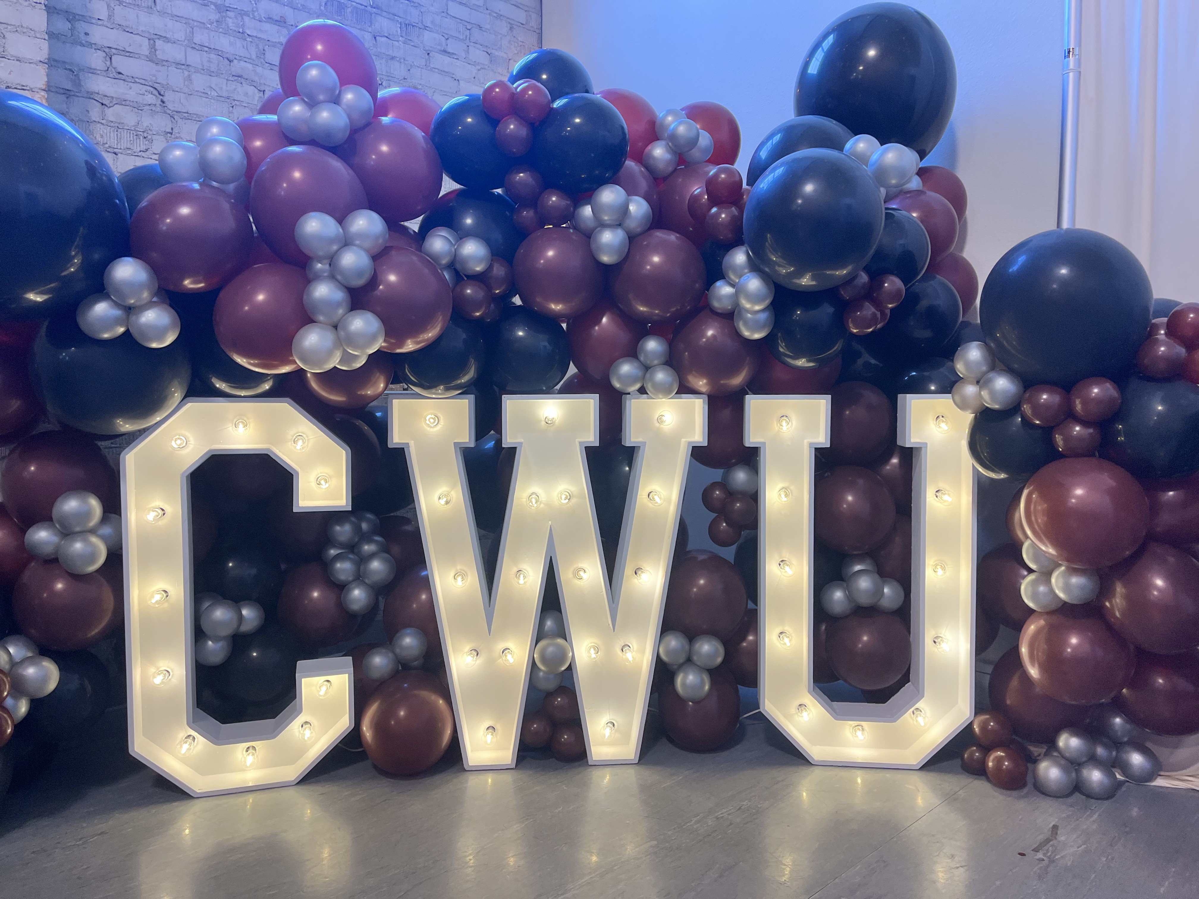 Light-up CWU marquee letters with a crimson, black and silver balloon garland at a Central Washington University graduation party at Host Wenatchee