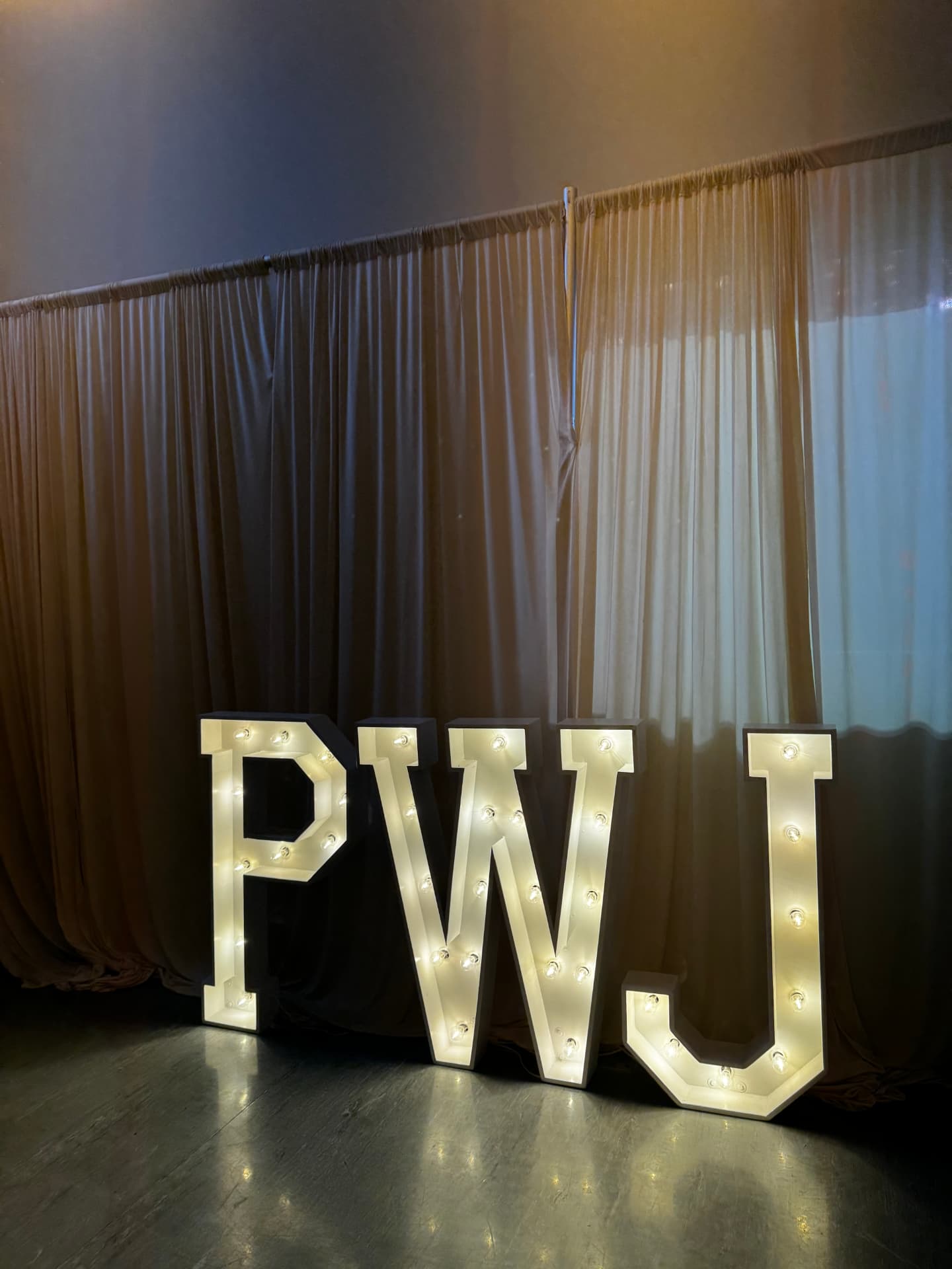 Custom PWJ light-up marquee letters against gold draping at a holiday company party at Host Wenatchee