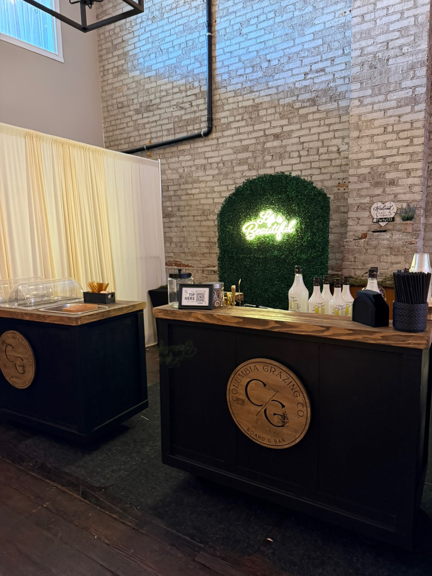 Grazing bar with neon sign and greenery wall set up for a celebration at Host Wenatchee