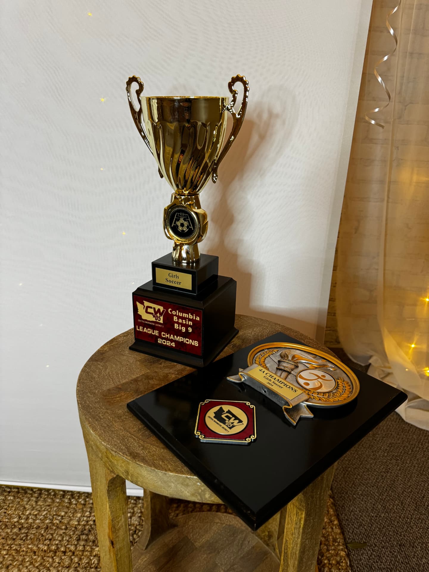 Championship trophy and plaques displayed on a wood side table at a celebration at Host Wenatchee