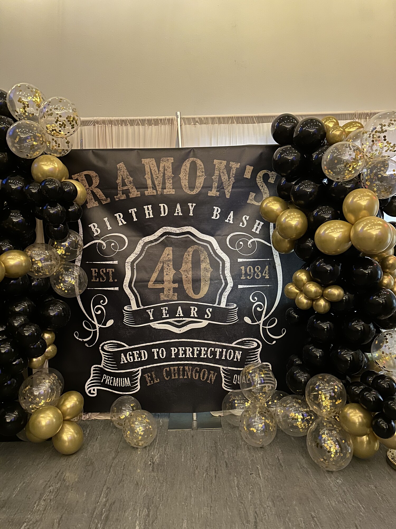 Black and gold balloon arch around a 40th birthday bash backdrop at Host Wenatchee