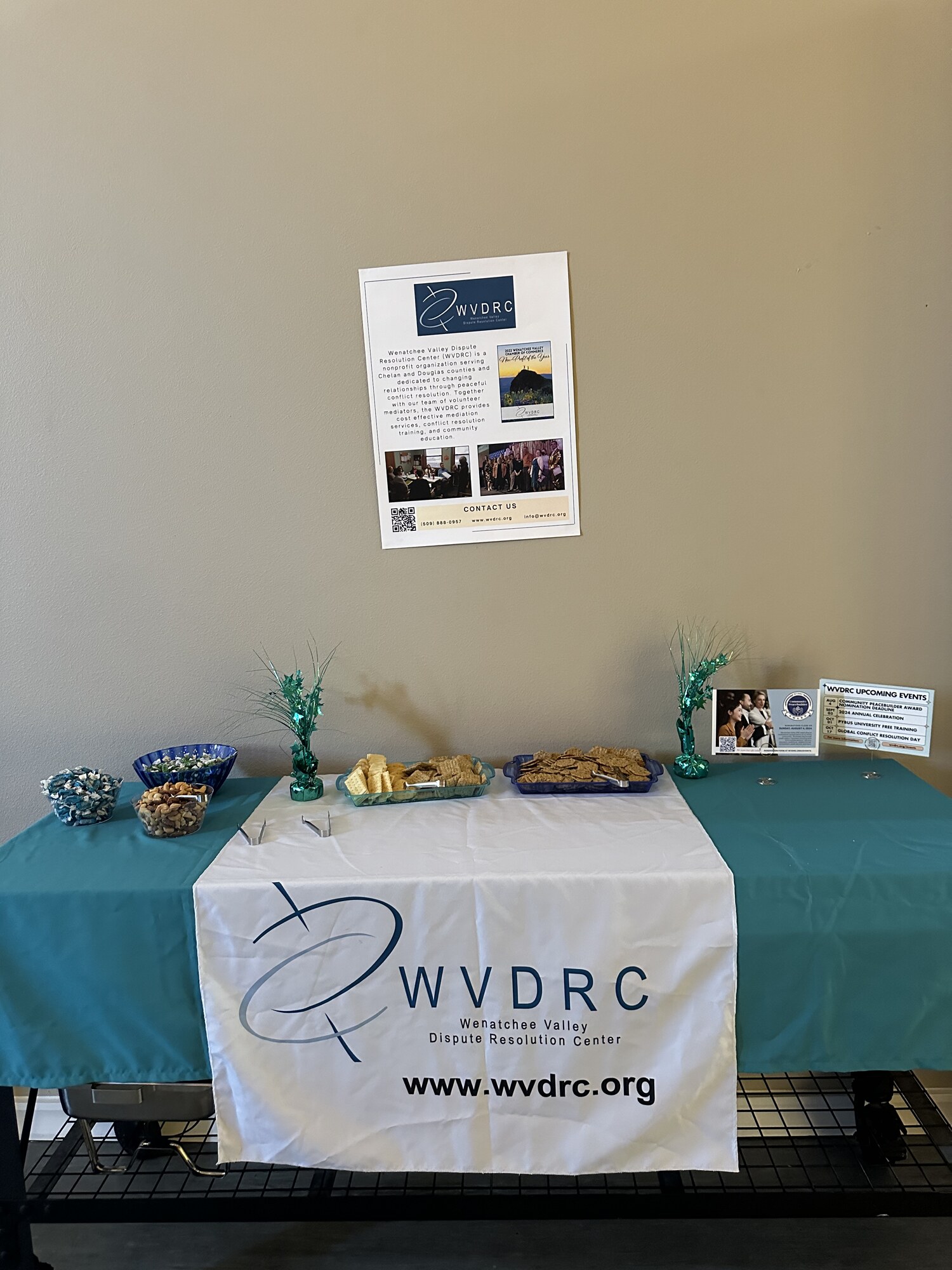Teal-linen snack table with crackers, nuts and branded table runner at a nonprofit annual celebration in Wenatchee